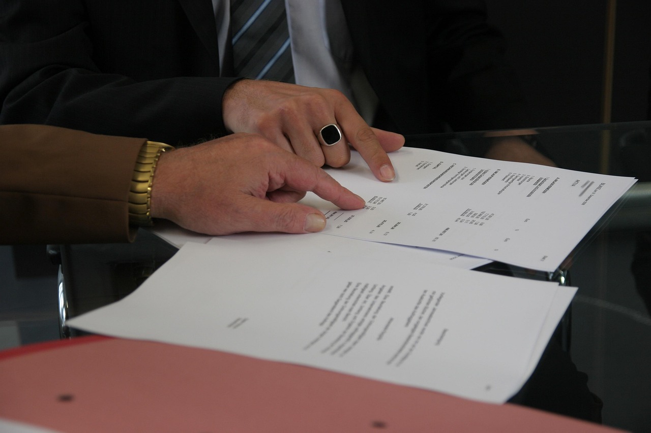 Two people pointing at the line items of a printed project quote and contract