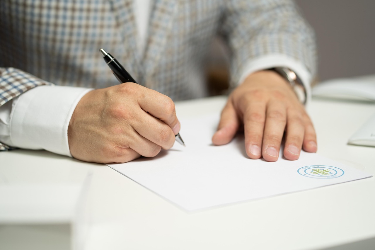 A person signing a web design agreement at a white desk